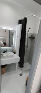 a white bathroom with a sink and a shower at Saris rooms in Pera Gyalos +27 photos