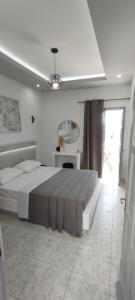 a white bedroom with a large bed and a window at Saris rooms in Pera Gyalos