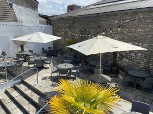 an outdoor patio with tables and chairs and umbrellas at The Castle Hotel Neath in Neath
