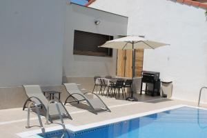 a pool with chairs and a table and an umbrella at La Alcoholera in Valtierra