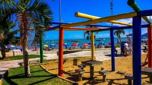 a colorful playground on a beach with people on the beach at Studio 187 in Rio das Ostras