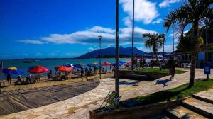 a group of people sitting under umbrellas on a beach at Studio 187 in Rio das Ostras