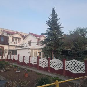 a fence in front of a house with a tree at CASA Ysy SUD in Eforie Sud