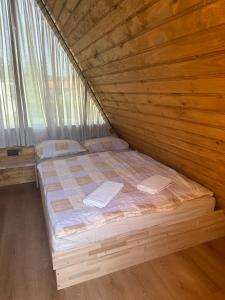 a bed in a room with a wooden wall at Hostel Ociski Raj in Kozina