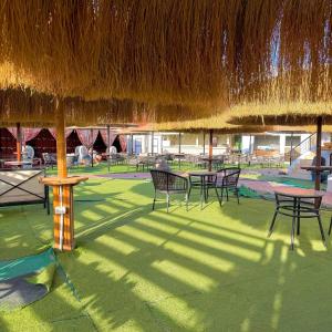 a patio with tables and chairs under a straw umbrella at Hurghada Porto View in Hurghada