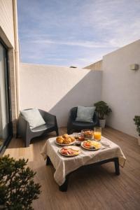 a table with plates of food on a patio at Entre Patios 1BR Costa Nova Beach in Gafanha da Encarnação