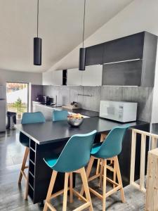 a kitchen with a black counter and blue chairs at Le refuge médiéval - Appartement climatisé perché sous les toits de Billom in Billom