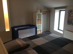 a bedroom with a bed and a cabinet and a window at Le refuge médiéval - Appartement climatisé perché sous les toits de Billom in Billom