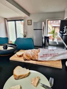 a table with a loaf of bread on a cutting board at Le refuge médiéval - Appartement climatisé perché sous les toits de Billom in Billom +7 photos