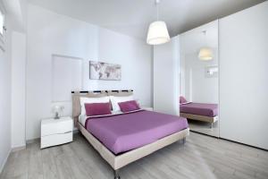 a white bedroom with a purple bed and a mirror at Amore Rentals - Villa Anna in Positano