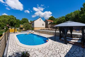 a swimming pool with an umbrella and a patio at My Dalmatia - Villa Manda Adriatic with Private Heated Pool in Skradin