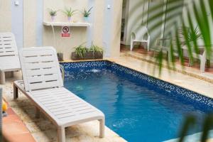 a swimming pool with two chairs next to a building at Casa Crespo in Cartagena de Indias