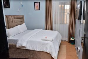 a bedroom with a bed with white sheets and a television at Peace Vil in Kuto
