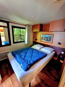 a bedroom with a bed with blue sheets and two windows at Camping Paus'Art Déco in Villemer +17 photos