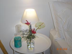 a table with a lamp and a vase with flowers on it at Le Jardin Secret in Le Vauclin