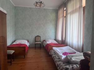 a room with two beds and a chair and a window at Likhauri Guesthouse in Likhauri