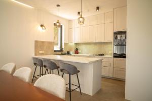 a kitchen with white cabinets and a island with bar stools at Elysium Villa in Kaluđerac