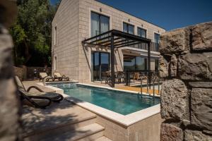 a house with a swimming pool in front of a building at Elysium Villa in Kaluđerac