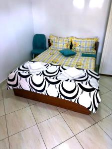 a bed with a black and white comforter and a blue chair at Casa Denisa in Sulina