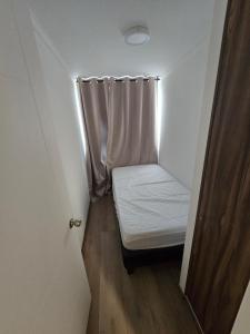 a small bed in a small room with a curtain at Baquedano in Coquimbo