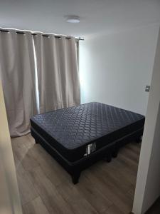 a bed sitting in a room next to a window at Baquedano in Coquimbo