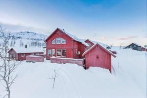 a red house with snow in front of it at RIBO Apartment Katterjåkk in Riksgränsen
