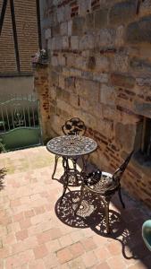 a table and chair sitting next to a brick wall at Ecrin d'exception avec jacuzzi et salon cinéma in Penne-dʼAgenais