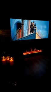 two people on a boat with candles in front of a tv at Ecrin d'exception avec jacuzzi et salon cinéma in Penne-dʼAgenais