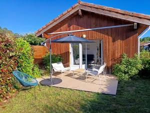 a patio with two chairs and an umbrella at Appartement proche lac et plage in Léon