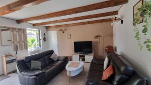 a living room with a black leather couch and a tv at Maison de Pierre in Septfonds
