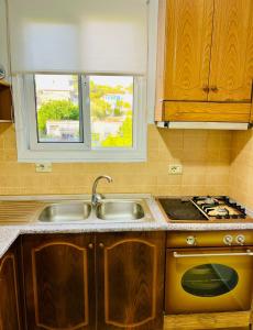 a kitchen with a sink and a stove and a window at Seren Apartment in Vlorë +4 photos