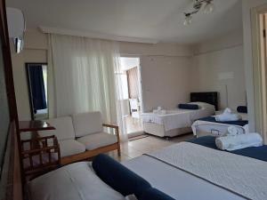 a bedroom with two beds and a living room with a couch at Hotel Antonio in Çeşme +46 photos