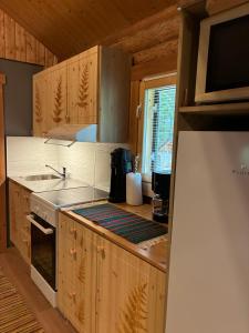 a kitchen with wooden cabinets and a sink and a refrigerator at Kytötupa in Keuruu