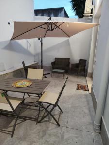 a patio with a table and chairs and an umbrella at Casa Aurora & Santiago in Trapani