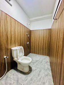 a bathroom with a toilet and wooden walls at Friendly Waves Resort Arugambay in Pottuvil +48 photos
