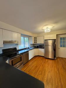 a large kitchen with stainless steel appliances and wooden floors at Spacious Cottage Style Home in Toronto +18 photos