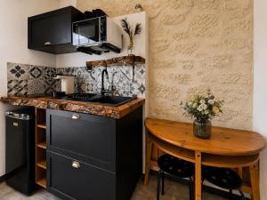 a kitchen with black cabinets and a wooden table at L inarretable studio independant in Cézac