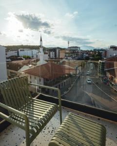 ein Stuhl auf einem Balkon mit Blick auf eine Stadt in der Unterkunft Noir Hotel in Gjakove