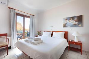une chambre avec un grand lit blanc et une fenêtre dans l'établissement Pramataris, à Monemvasia