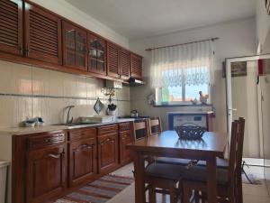 a kitchen with wooden cabinets and a table with chairs at Casa Afonso Guesthouse in Ferrel