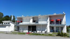 a white building with red umbrellas on the balconies at Staylong Hotell in Täby