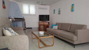 a living room with two couches and a tv at Phiniscollis B&B in La Caletta