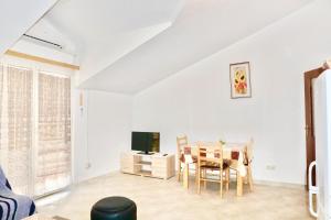 ein Wohnzimmer mit einem Tisch und einem Fernseher in der Unterkunft Rosette suites Trogir Seget Vranjica in Seget Vranjica