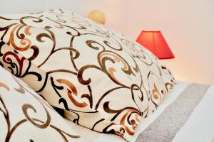 ein Bett mit einer braun-weißen Bettdecke und einer roten Lampe in der Unterkunft Rosette suites Trogir Seget Vranjica in Seget Vranjica