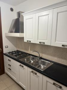 a kitchen with white cabinets and a sink at Illumina House 2 in Giurdignano