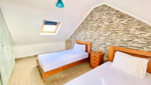 a bedroom with two beds and a brick wall at O Cantinho do Pargo in Ponta do Pargo
