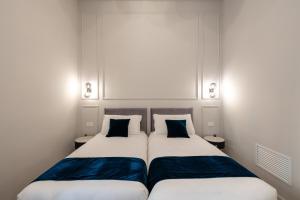 two beds in a small room with blue pillows at Aethel Guesthouse in Rome