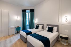 two beds in a hotel room with green curtains at Aethel Guesthouse in Rome