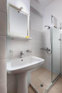 une salle de bains blanche avec un lavabo et un miroir dans l'établissement Pramataris, à Monemvasia