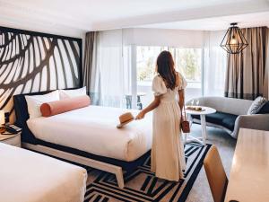 a woman standing next to a bed in a hotel room at Pullman Cairns International in Cairns +179 photos
